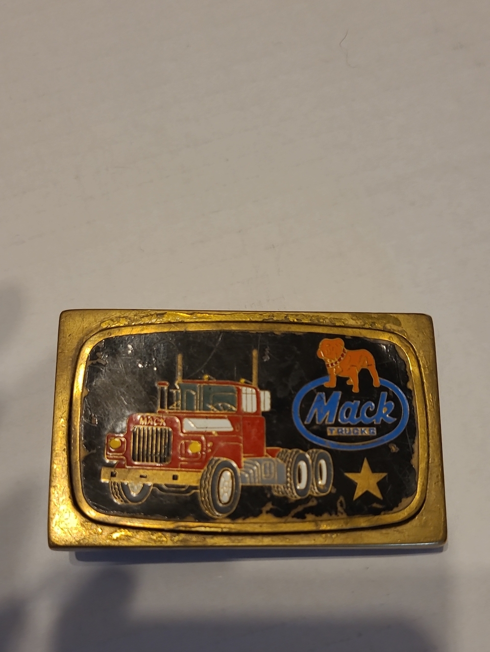 Vintage brass belt buckle features the  red Mack Truck R-model along A BULL DOG